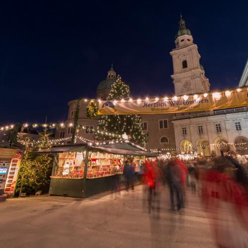 Mercatino d'Avvento a Salisburgo con luci, neve, bancarelle ecampanile della chiesa di notte